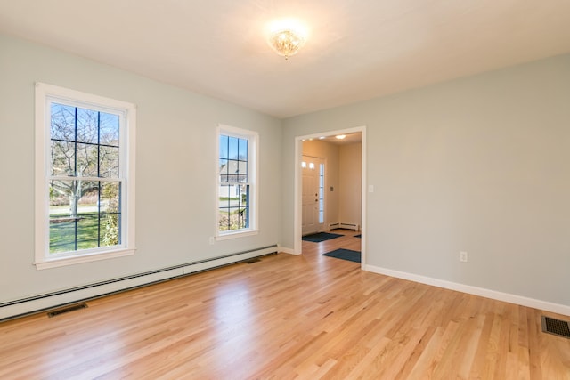 unfurnished room featuring baseboard heating, baseboards, visible vents, and light wood-style flooring
