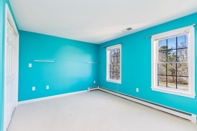 carpeted empty room featuring visible vents, baseboards, a baseboard heating unit, and a healthy amount of sunlight
