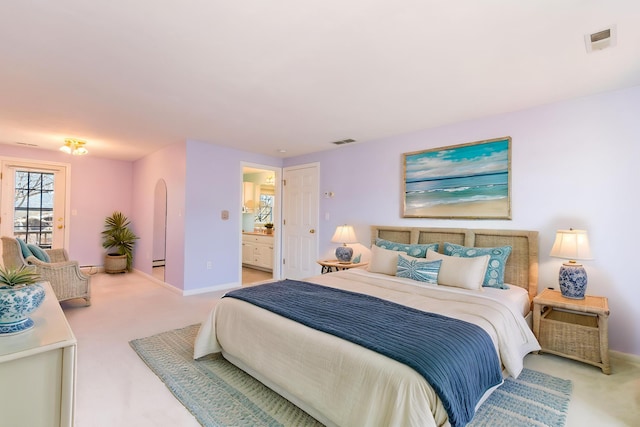 carpeted bedroom with arched walkways, ensuite bath, visible vents, and baseboards