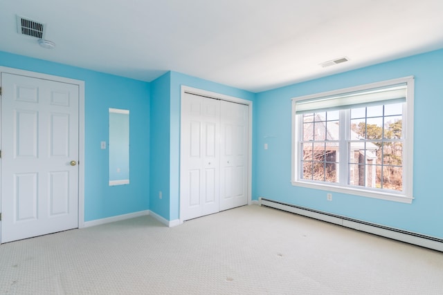 unfurnished bedroom featuring a baseboard radiator, a closet, visible vents, and carpet floors