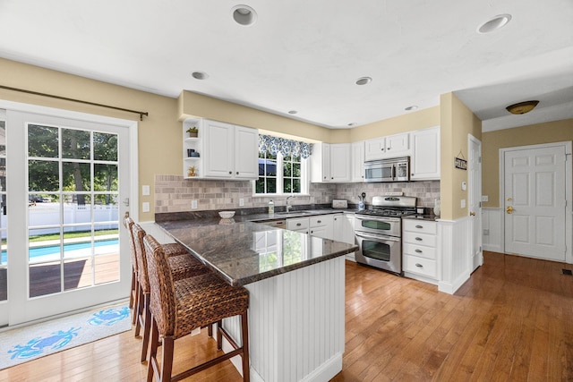 67 Sea Meadow Cir, Centerville, MA 02632 - kitchen with stainless steel appliances, white cabinetry, light wood-type flooring, a breakfast bar area, and recessed lighting