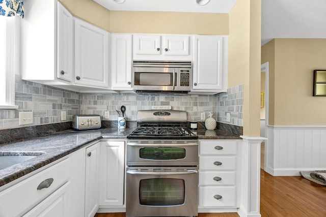 67 Sea Meadow Cir, Centerville, MA 02632 - kitchen with stainless steel appliances, white cabinetry, light wood finished floors, wainscoting, and decorative backsplash