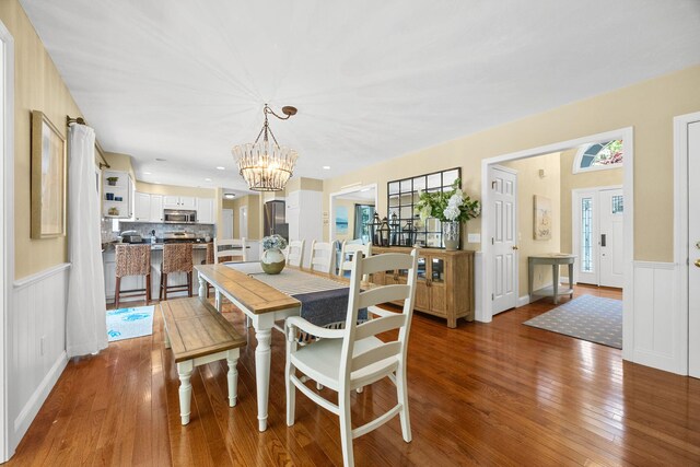 67 Sea Meadow Cir, Centerville, MA 02632 - dining area with hardwood / wood-style floors, a chandelier, and a wainscoted wall