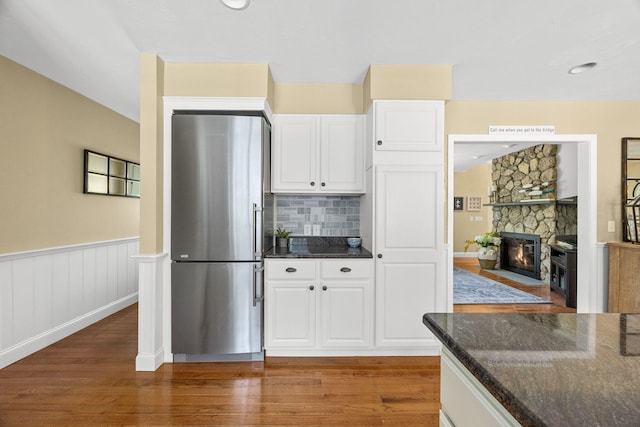 67 Sea Meadow Cir, Centerville, MA 02632 - kitchen featuring freestanding refrigerator, dark stone counters, wood finished floors, white cabinets, and a stone fireplace
