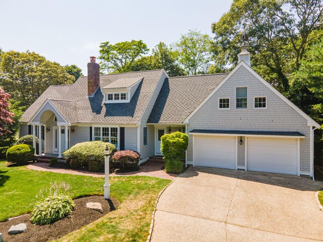 67 Sea Meadow Cir, Centerville, MA 02632 - shingle-style home with concrete driveway, a chimney, a front yard, a shingled roof, and an attached garage
