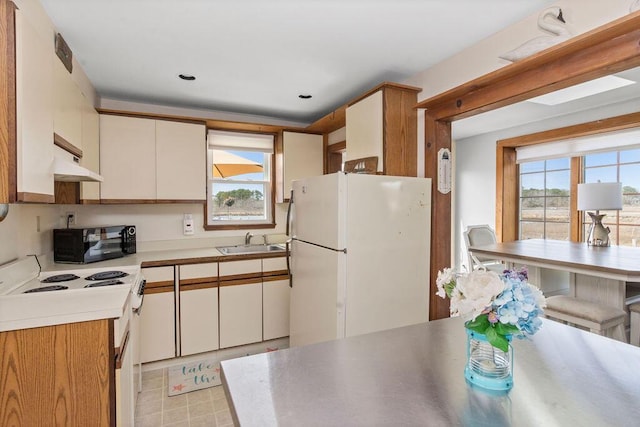 kitchen with white cabinets, a sink, white appliances, light countertops, and under cabinet range hood