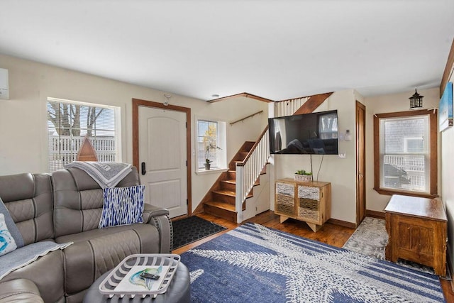 living room featuring stairs, baseboards, plenty of natural light, and wood finished floors