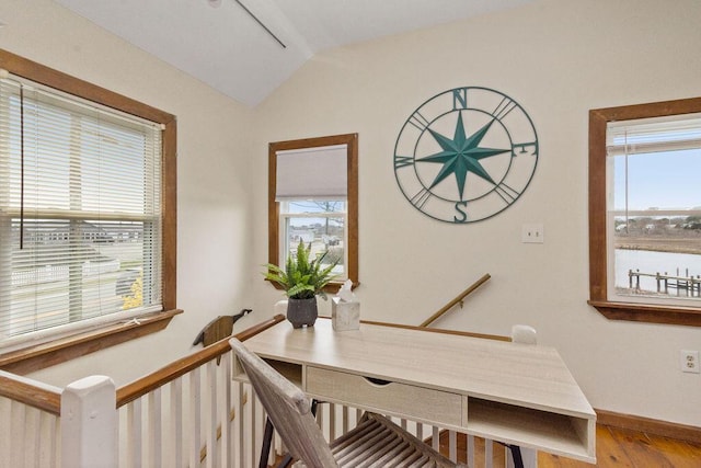 interior space featuring baseboards, wood finished floors, and vaulted ceiling