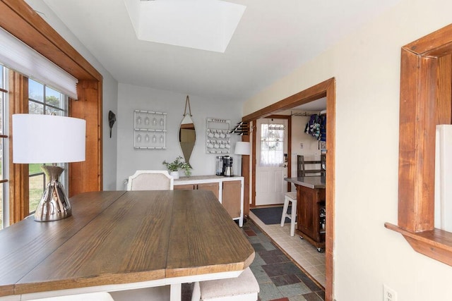 dining space with a skylight and stone finish flooring