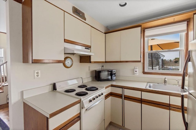 kitchen featuring a sink, light countertops, white cabinetry, under cabinet range hood, and white electric range