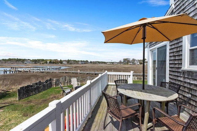 deck with outdoor dining area and a water view