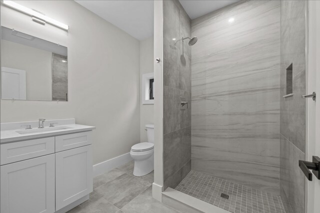 bathroom with toilet, vanity, and a tile shower