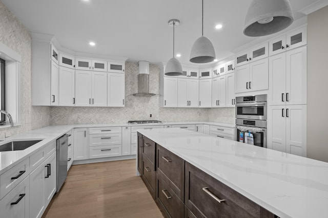 kitchen with wall chimney exhaust hood, sink, white cabinets, stainless steel appliances, and dark brown cabinetry