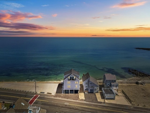 aerial view at dusk featuring a water view