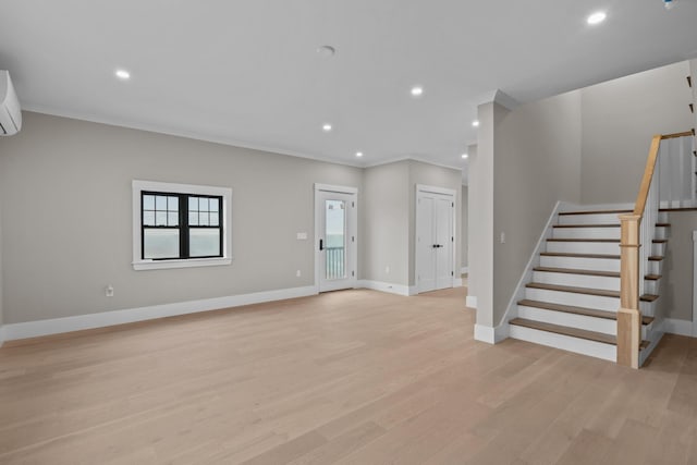 unfurnished living room featuring a wall mounted air conditioner, light hardwood / wood-style flooring, and crown molding