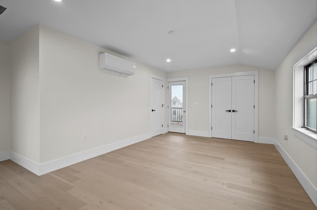 interior space with vaulted ceiling, light hardwood / wood-style flooring, and a wall unit AC