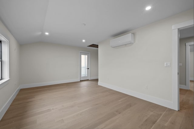 empty room featuring a wall mounted AC, light hardwood / wood-style flooring, and a healthy amount of sunlight