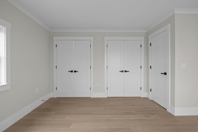 interior space with light wood-type flooring, two closets, and ornamental molding