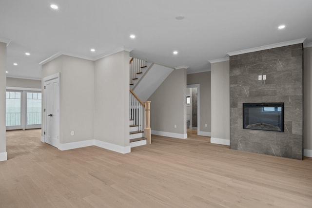 unfurnished living room featuring crown molding, a tiled fireplace, and light hardwood / wood-style floors