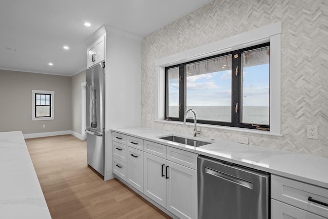 kitchen featuring sink, crown molding, light stone counters, and stainless steel appliances