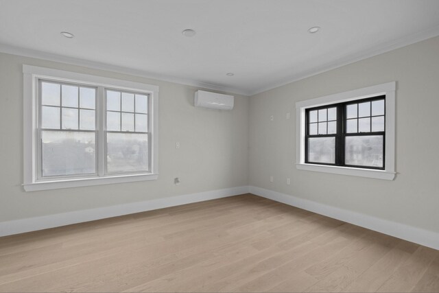 unfurnished room featuring an AC wall unit, ornamental molding, and light wood-type flooring