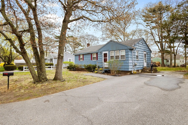 74 Fearing St, Buzzards Bay, MA 02532 - view of front of home featuring asphalt driveway, roof with shingles, a chimney, and a residential view