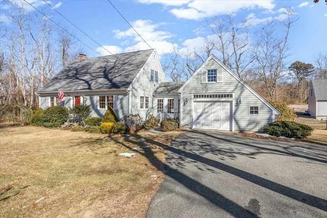 new england style home with driveway, a front lawn, a chimney, and an attached garage