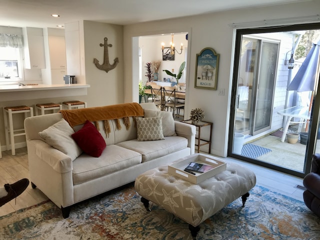 living room featuring a chandelier, plenty of natural light, and light wood-style flooring