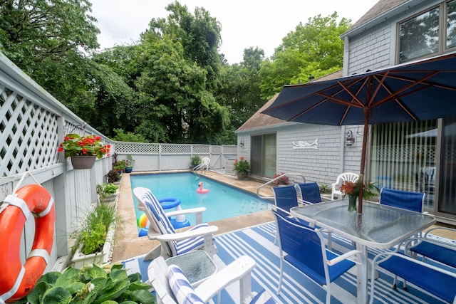 view of swimming pool featuring outdoor dining space, a fenced backyard, a fenced in pool, and a patio