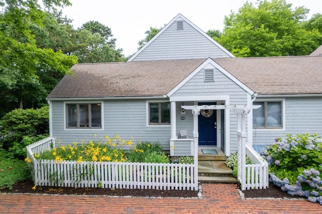 bungalow featuring fence and roof with shingles