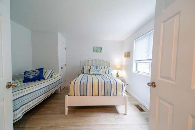 bedroom with wood finished floors, visible vents, and baseboards