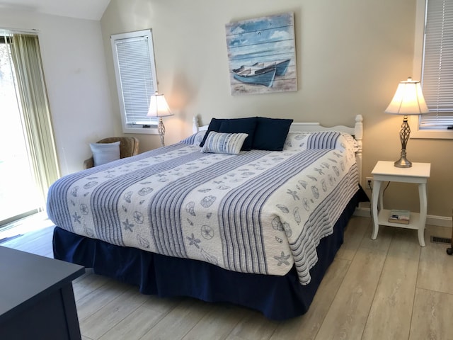 bedroom featuring lofted ceiling, visible vents, baseboards, and hardwood / wood-style floors