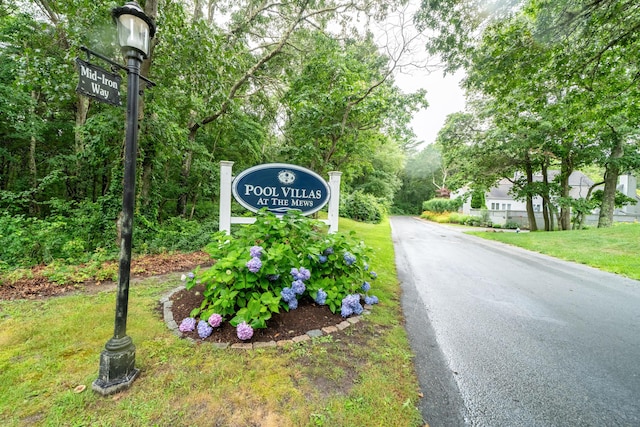 community / neighborhood sign with aphalt driveway and a lawn