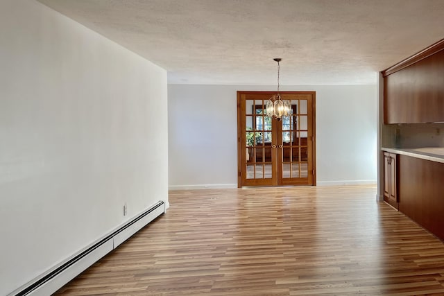 unfurnished dining area featuring a baseboard radiator, light hardwood / wood-style floors, a textured ceiling, and a notable chandelier