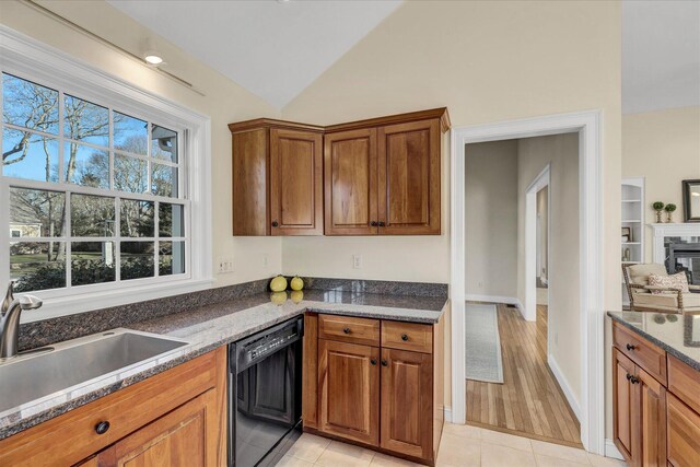 kitchen with black dishwasher, light tile patterned floors, sink, dark stone countertops, and lofted ceiling