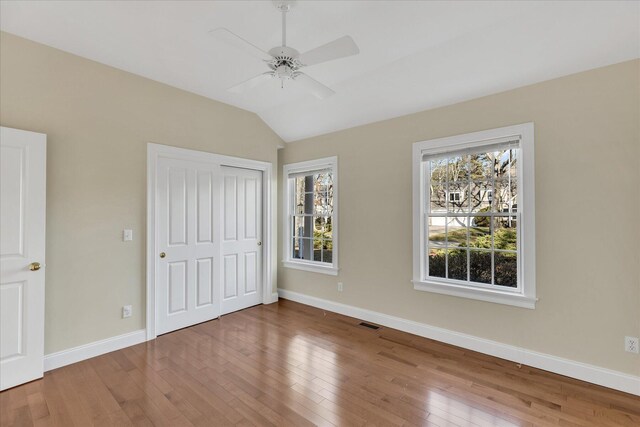 unfurnished bedroom featuring lofted ceiling, hardwood / wood-style floors, a closet, and ceiling fan