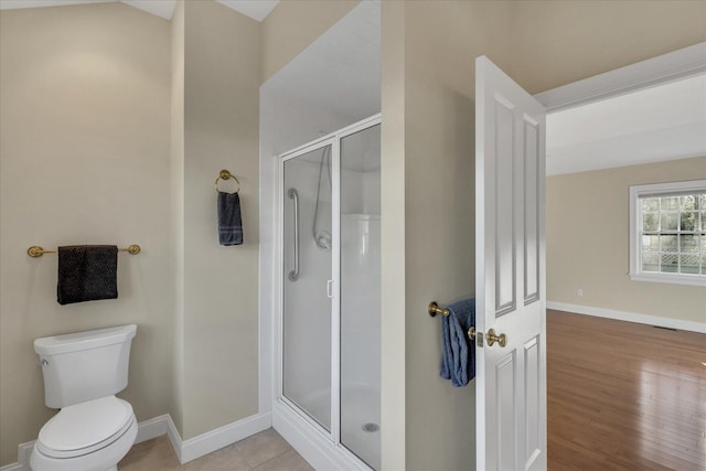 bathroom featuring toilet, an enclosed shower, and tile patterned floors