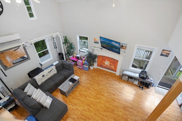 452 Nathan Ellis Hwy, Mashpee, MA 02649 - living area featuring a towering ceiling, wood finished floors, a warm lit fireplace, and a wall mounted AC