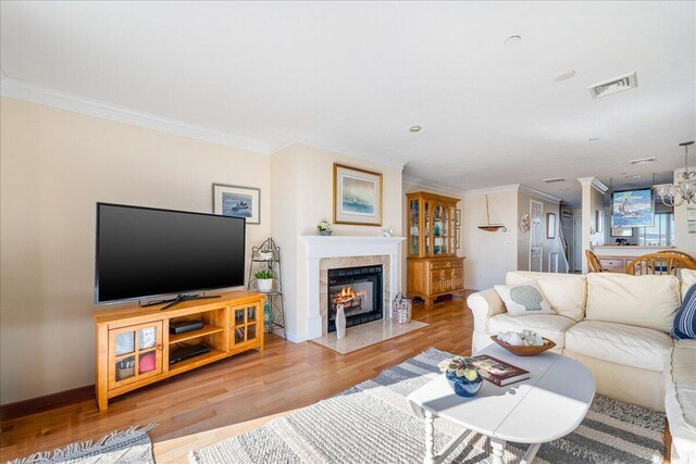 29 Highland Ter Unit 2903, Plymouth, MA 02360 - living area featuring light wood-style flooring, a fireplace with flush hearth, ornamental molding, baseboards, and a chandelier