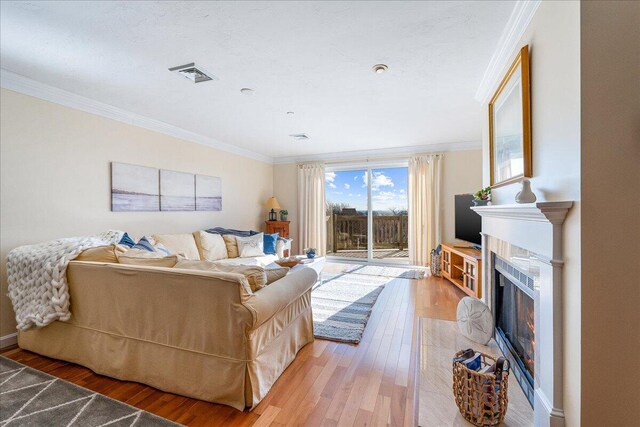 29 Highland Ter Unit 2903, Plymouth, MA 02360 - living area featuring crown molding, light wood finished floors, a warm lit fireplace, and baseboards