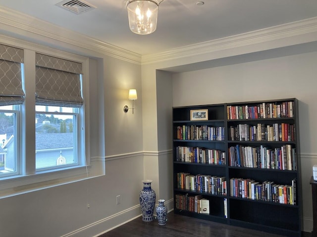 interior space with baseboards, wood finished floors, visible vents, and crown molding