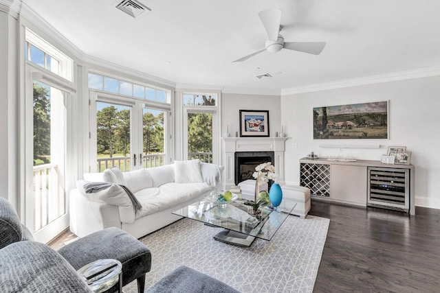 living room with wine cooler, plenty of natural light, visible vents, and crown molding