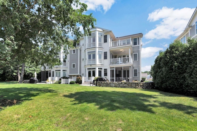 rear view of house with a balcony and a yard