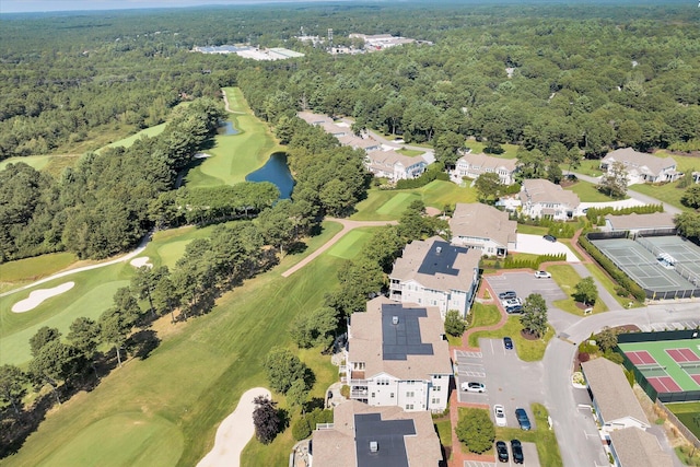 drone / aerial view with view of golf course, a forest view, a water view, and a residential view