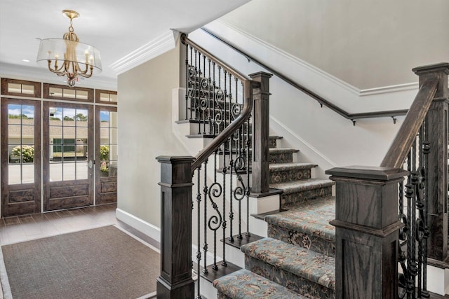 entryway featuring a notable chandelier, wood finished floors, stairs, and crown molding