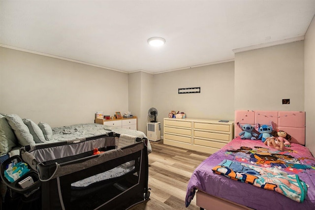 bedroom featuring crown molding and light hardwood / wood-style flooring