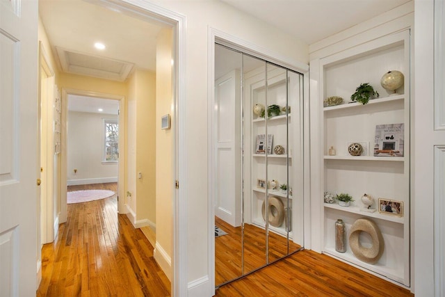 hallway with hardwood / wood-style flooring and built in shelves