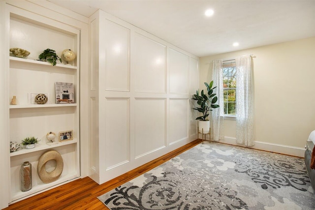 interior space with built in shelves and wood-type flooring