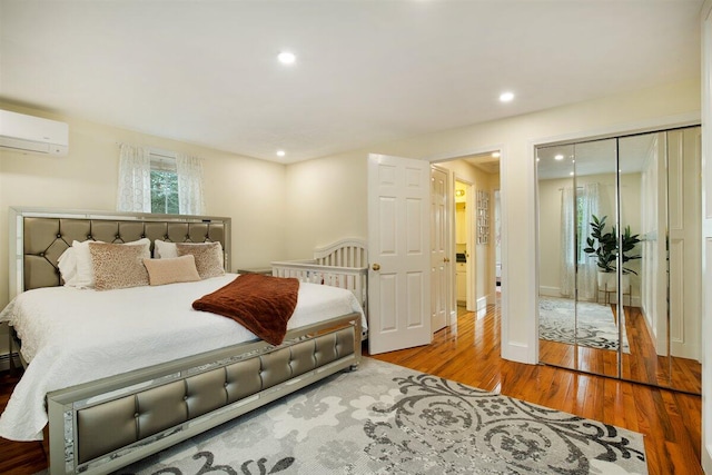 bedroom featuring an AC wall unit, a closet, and light wood-type flooring