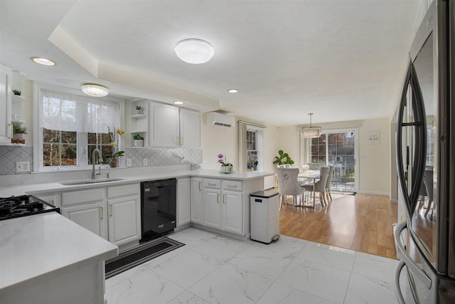 kitchen featuring sink, hanging light fixtures, stainless steel refrigerator, kitchen peninsula, and black dishwasher